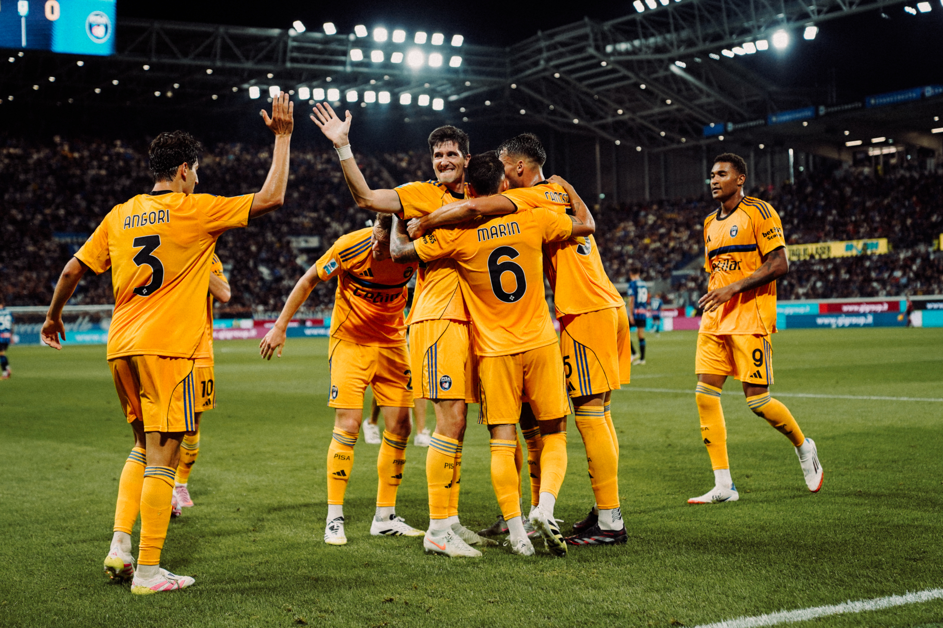 Pisa Sporting Club players celebrating a goal in the yellow away kit
